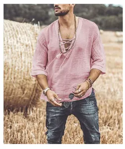 Detail of pink men's V-neck linen shirt with lace-up collar in a rustic field setting.