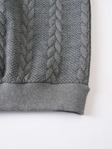 Primo piano della trama trapuntata jacquard grigia e dell'orlo a coste di una felpa da uomo.