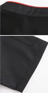 Primo piano del tessuto nero traspirante e del profilo rosso del colletto da cuoco.