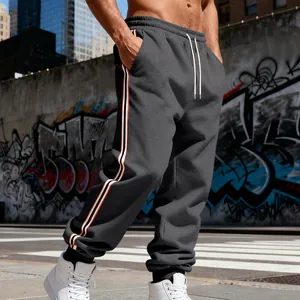 Dettaglio di joggers grigi con strisce laterali atletiche in un ambiente urbano.
