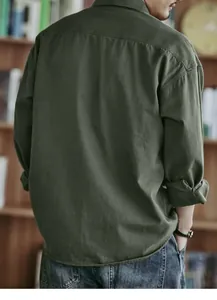 Back view of men's vintage olive green long sleeve utility shirt in a cozy library