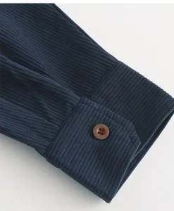 Primo piano del polsino di una camicia di velluto a coste blu con bottone marrone