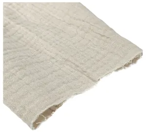 Macro detail of breathable textured cotton gauze fabric with frayed raw edge finish