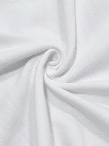 Gros plan détaillé montrant la texture respirante du tissu en coton et lin blanc du haut