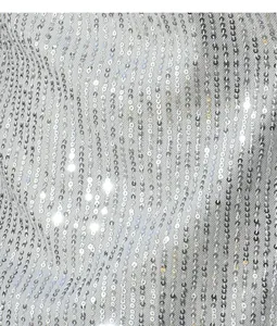 Dettaglio ravvicinato della trama del tessuto con paillettes argento sulla camicia