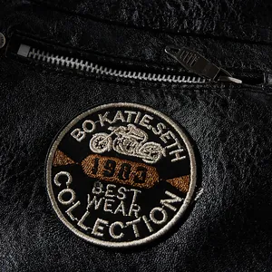 Nahaufnahme einer schwarzen PU-Leder-Motorradjacke mit gesticktem Motorrad-Patch-Detail.
