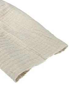 Detailed close-up of breathable beige cotton shirt sleeve featuring raw frayed edge design