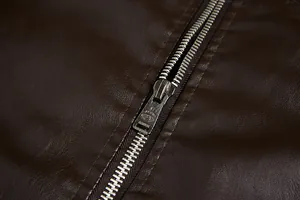Detailed macro shot of a durable silver metal zipper on a dark brown PU leather jacket sleeve.