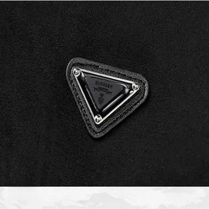 Détail macro d'un écusson logo triangulaire sur tissu en daim noir pour veste d'hiver vintage.