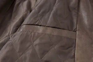 Detailopname van bruine doorgestikte voering en leren zakdetail van vintage jas.