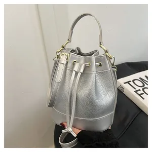Sac seau élégant en cuir grainé argenté avec ferrures dorées et fermeture à cordon coulissant