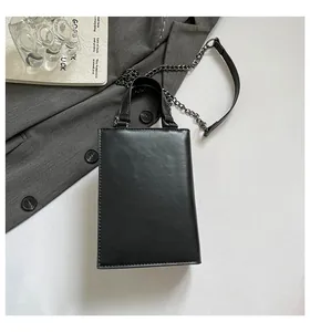 Stylish minimalist black box style handbag on grey blazer with metal chain strap