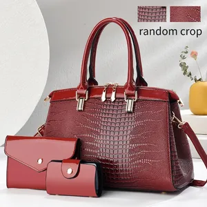 Detailed view of burgundy crocodile embossed 3-piece handbag set with gold hardware