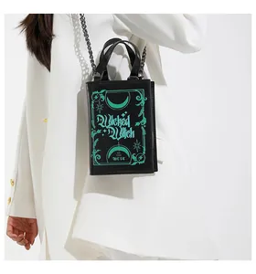 Detail shot of the Wicked Witch book-shaped crossbody bag with vibrant green print