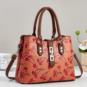 Close-up detail of cherry print and gold hardware on a stylish brown leather bag