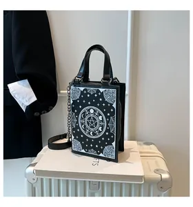Unique black book-shaped crossbody bag featuring mystical moon and star graphic prints