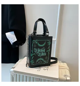 Detail view of a niche book-shaped black handbag with green Wicked Witch graphics