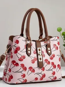 Elegant pink women's handbag with vibrant red cherry print and brown leather handles