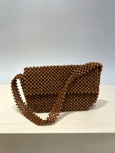 Dettaglio della trama di perline di legno intrecciate a mano di questa borsa marrone.