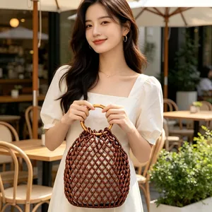 Modella tiene una borsa in grani di legno marrone intrecciata a mano in un caffè