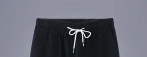 Détail d'un short en coton noir pour homme avec taille élastique et cordon de serrage blanc.