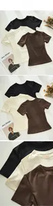 Detail view of three short-sleeved slim fit t-shirts in black, cream, and brown colors