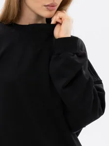 Close-up detail of a minimalist black thick crewneck sweatshirt with ribbed cuffs