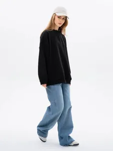 Street style view of oversized black crewneck sweatshirt with wide-leg denim jeans