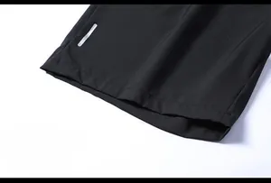 Dettaglio dei pantaloncini sportivi neri con apertura gamba ampia e striscia riflettente
