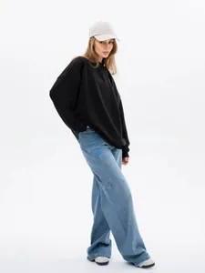 Full length photo of a model in a minimalist oversized black crewneck sweatshirt and jeans