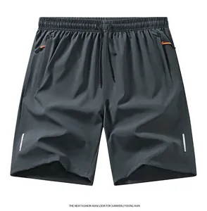 Dettaglio dei pantaloncini sportivi grigi con strisce riflettenti e zip arancio.