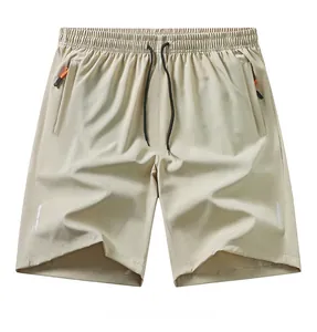 Dettaglio di pantaloncini sportivi beige con strisce riflettenti e tasche chiuse con cerniera.