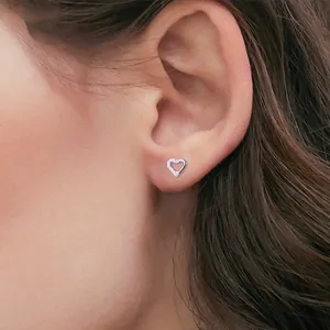 Close-up detail of a silver heart-shaped titanium stud earring worn on a model's ear
