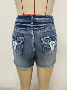 Back view detail of vintage blue denim shorts featuring boho embroidery and raw hem.