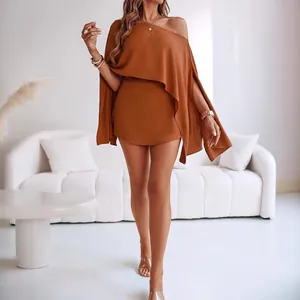 Elegant brown one-shoulder mini dress with cape sleeves shown in a modern interior setup.