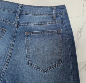 Détail de la poche arrière et des coutures orange sur un jean en denim délavé bleu