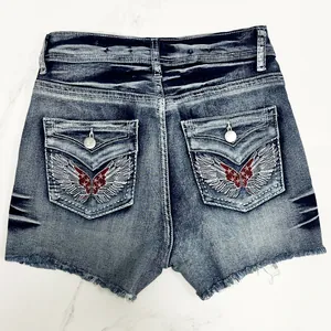 Detailed back view of vintage denim shorts with wing embroidery and raw fringe hem.