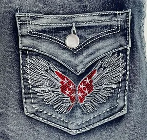 Detailed close-up of red and white wing embroidery with stars on vintage denim pocket