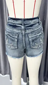 Close-up detail showing back pocket embroidery and frayed hem on blue denim shorts