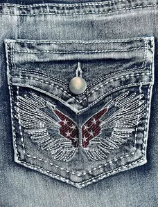 Detailed macro view showing the vintage wings embroidery on denim shorts back pocket