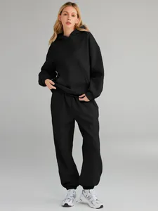 Full body shot of a female model wearing a black oversized hoodie and jogger set.