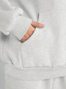 Close-up detail of grey hooded sweatshirt kangaroo pocket and soft ribbed cuff texture