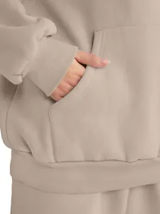 Detail view showing kangaroo pocket and ribbed cuffs of oversized beige hoodie sweatshirt