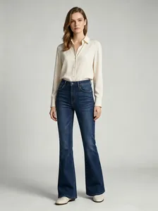 Elegant model posing in high-waisted dark blue flared jeans paired with a silk shirt