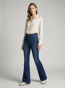 Fashion model posing in high-waisted dark blue flare jeans and a classic cream blouse