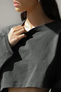 Detail view showing the fabric texture and round neckline of a cropped charcoal sweatshirt