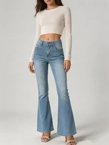 Detailed view of high-waisted light blue flared jeans worn by a model in studio