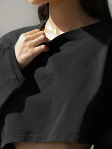 Detail view of a black cropped long-sleeve sweatshirt with a ribbed round neckline