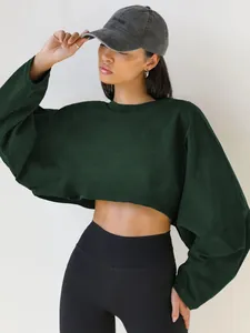 Close-up of a dark green cropped crewneck sweatshirt with oversized sleeves on a model