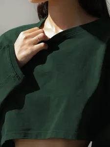 Close-up view of a dark green cropped sweatshirt showing ribbed knit fabric texture.
